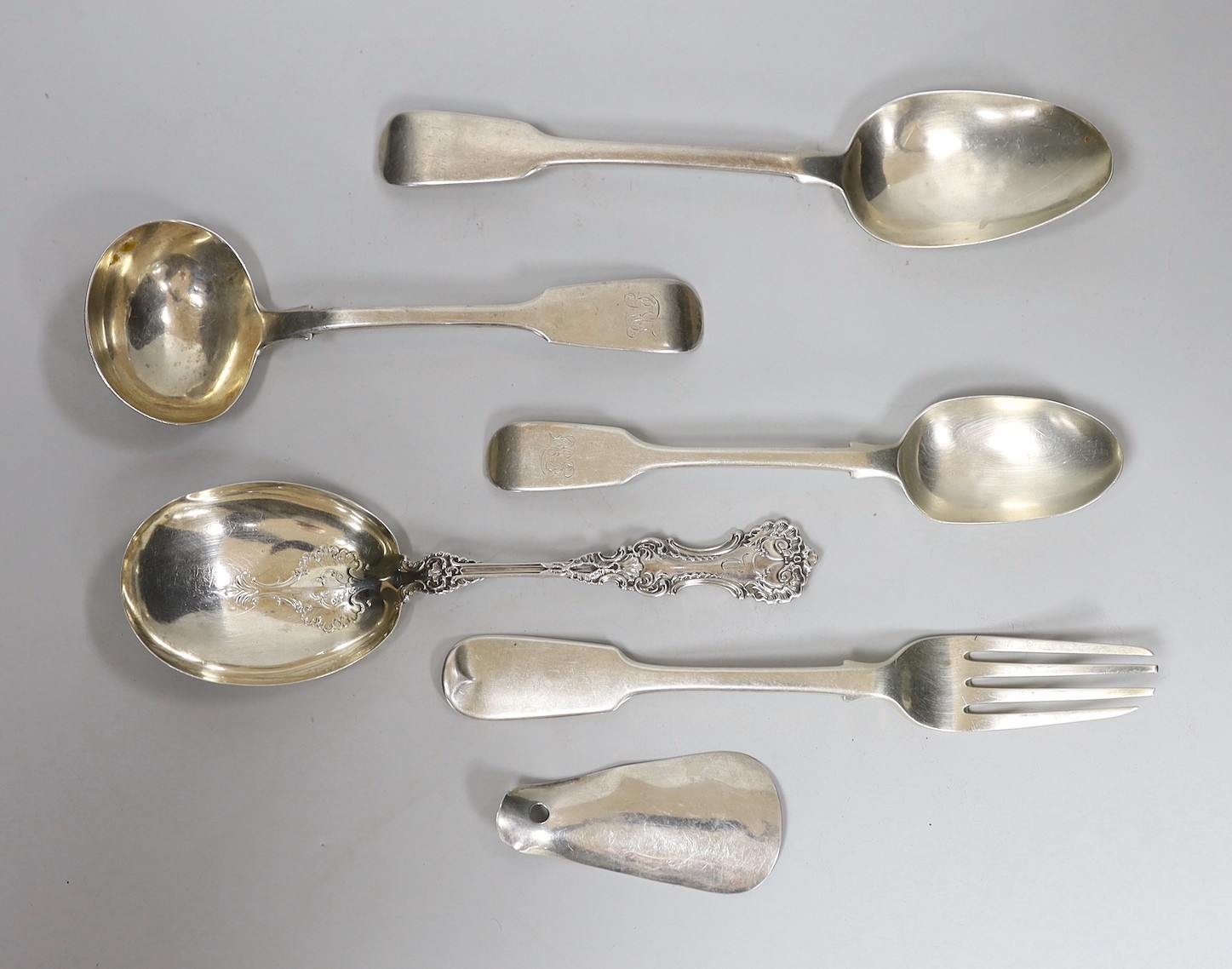 Four assorted items of silver flatware, a sterling serving spoon and a George V silver shoe horn (lacking ring), 10.6oz.